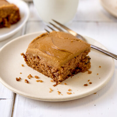 A slice of applesauce cake with easy penuche icing on a small plate.