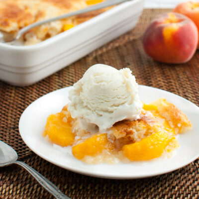 A serving of peach cobbler topped with a scoop of vanilla ice-cream.
