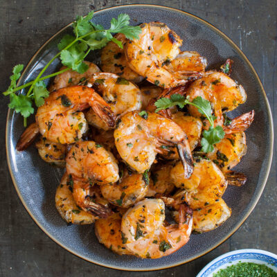 Overhead shot of some grilled shrimp on a gray plate.