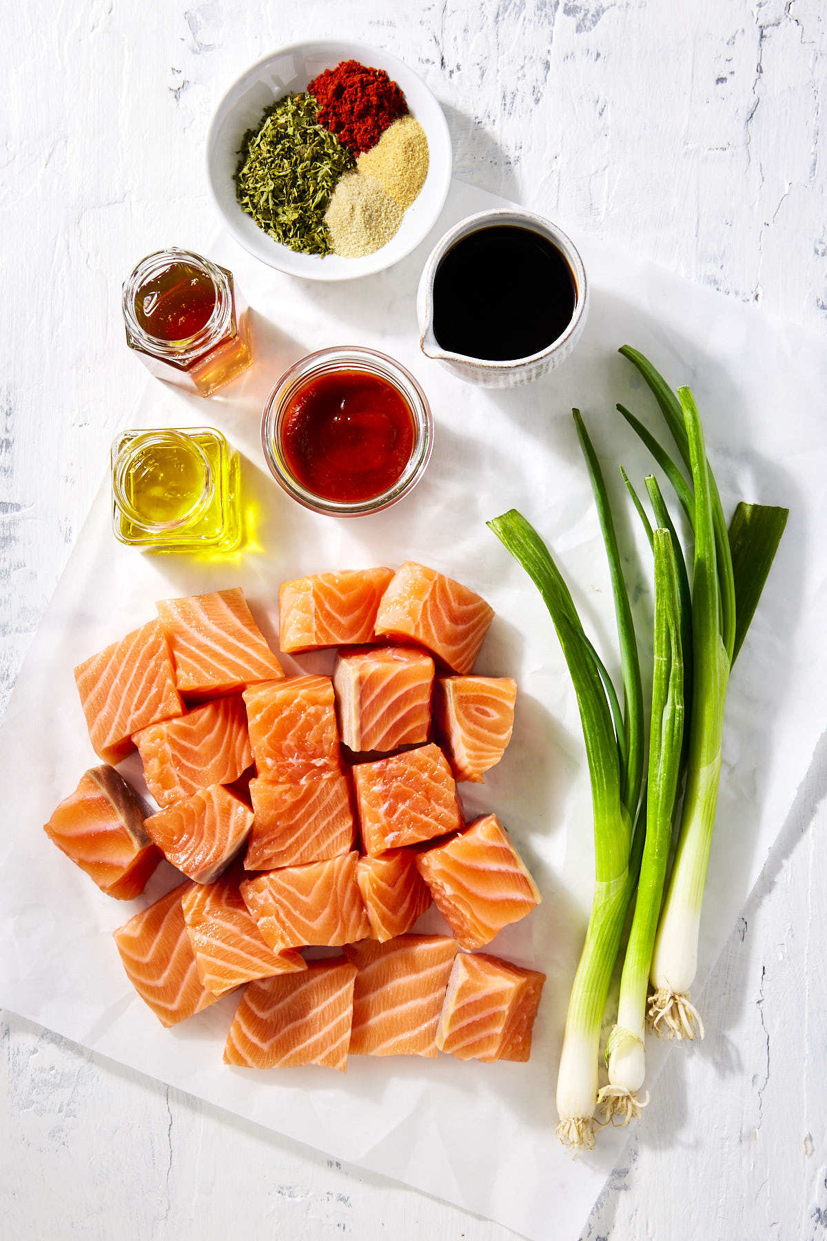 Ingredients to make honey sriracha salmon bites on a white background.