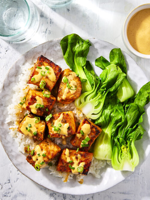 Honey sriracha salmon bites topped with some sriracha mayo sauce and chopped green onions.