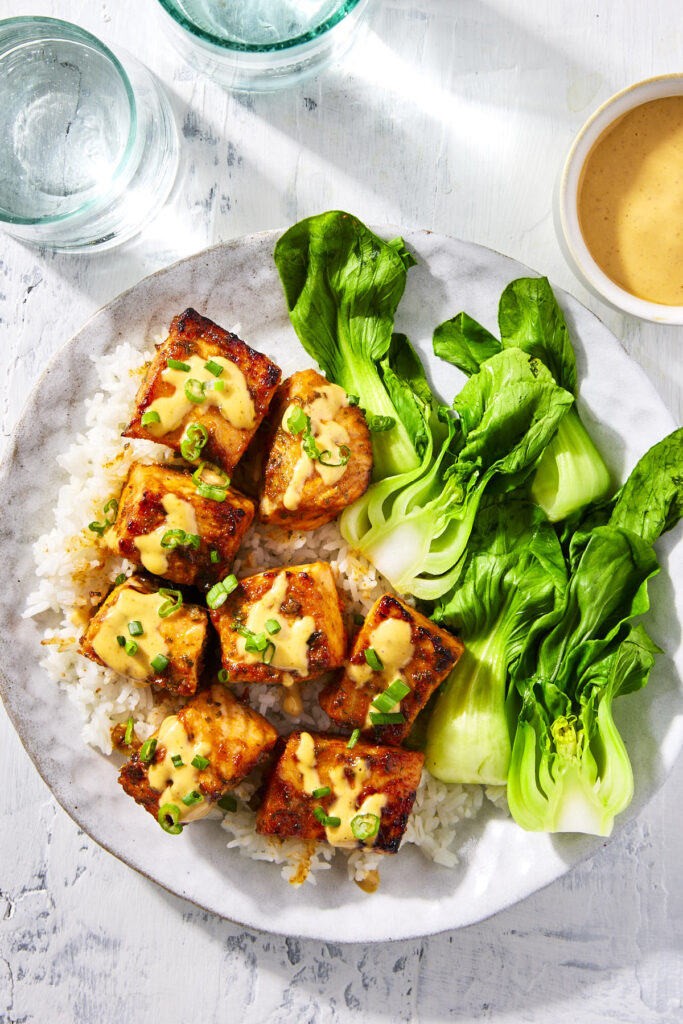 Honey sriracha salmon bites topped with some sriracha mayo sauce and chopped green onions.