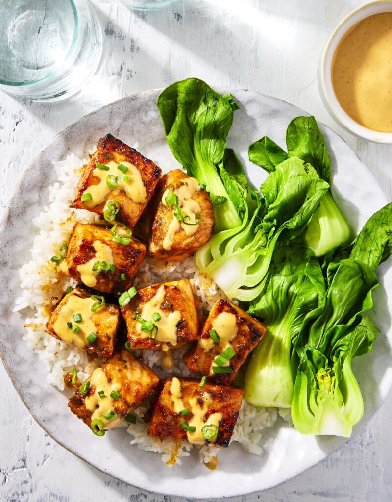 Honey sriracha salmon bites topped with some sriracha mayo sauce and chopped green onions.