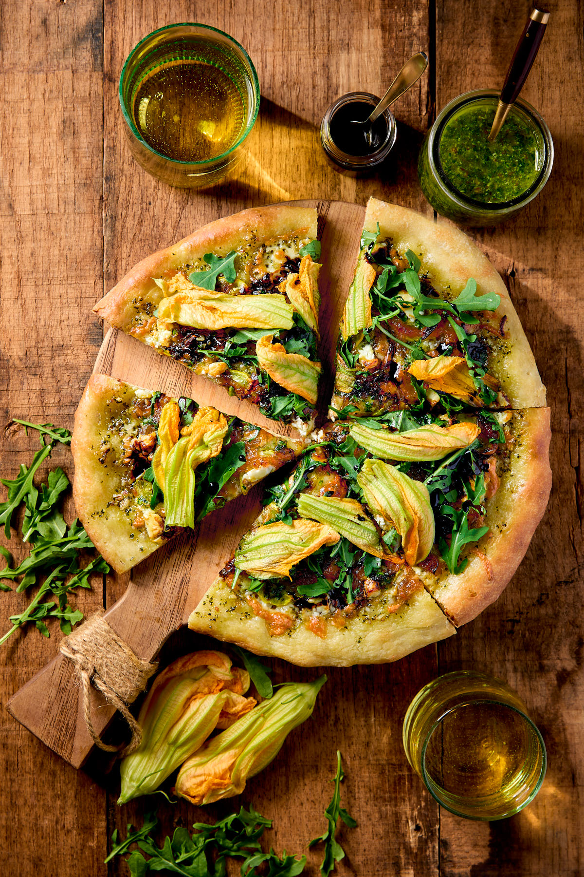 Slices of squash blossom pizza on a wooden board.
