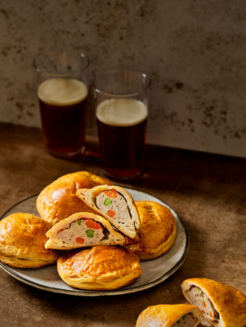 Some paté chaud on a gray plate next to glasses of beer.