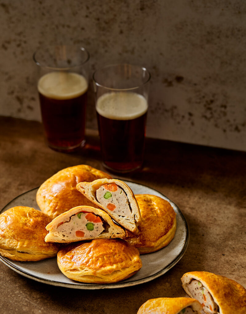 Some paté chaud on a gray plate next to glasses of beer.