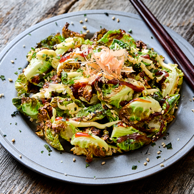 Plate of fried Brussels sprouts topped with katsu sauce, mayo, furikake, and bonito flakes.