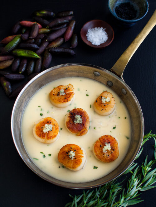 Seared scallops with finger lime beurre blanc in a sauté pan.