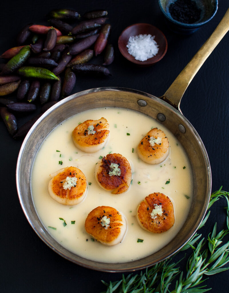 Seared scallops with finger lime beurre blanc in a sauté pan.