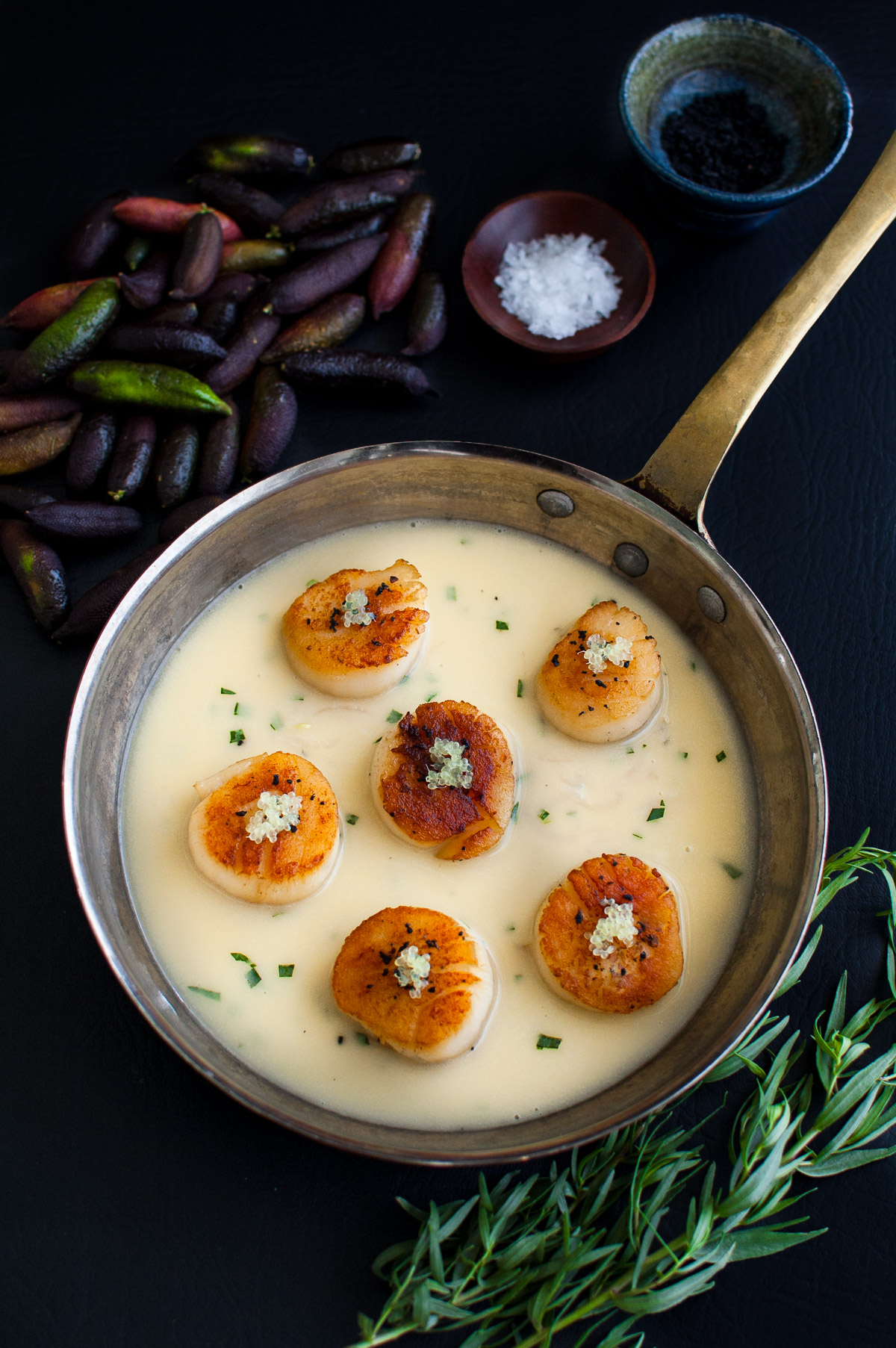 Seared scallops with finger lime beurre blanc in a sauté pan.