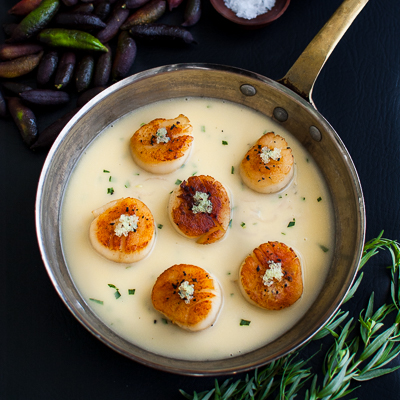 Seared scallops with finger lime beurre blanc in a sauté pan.