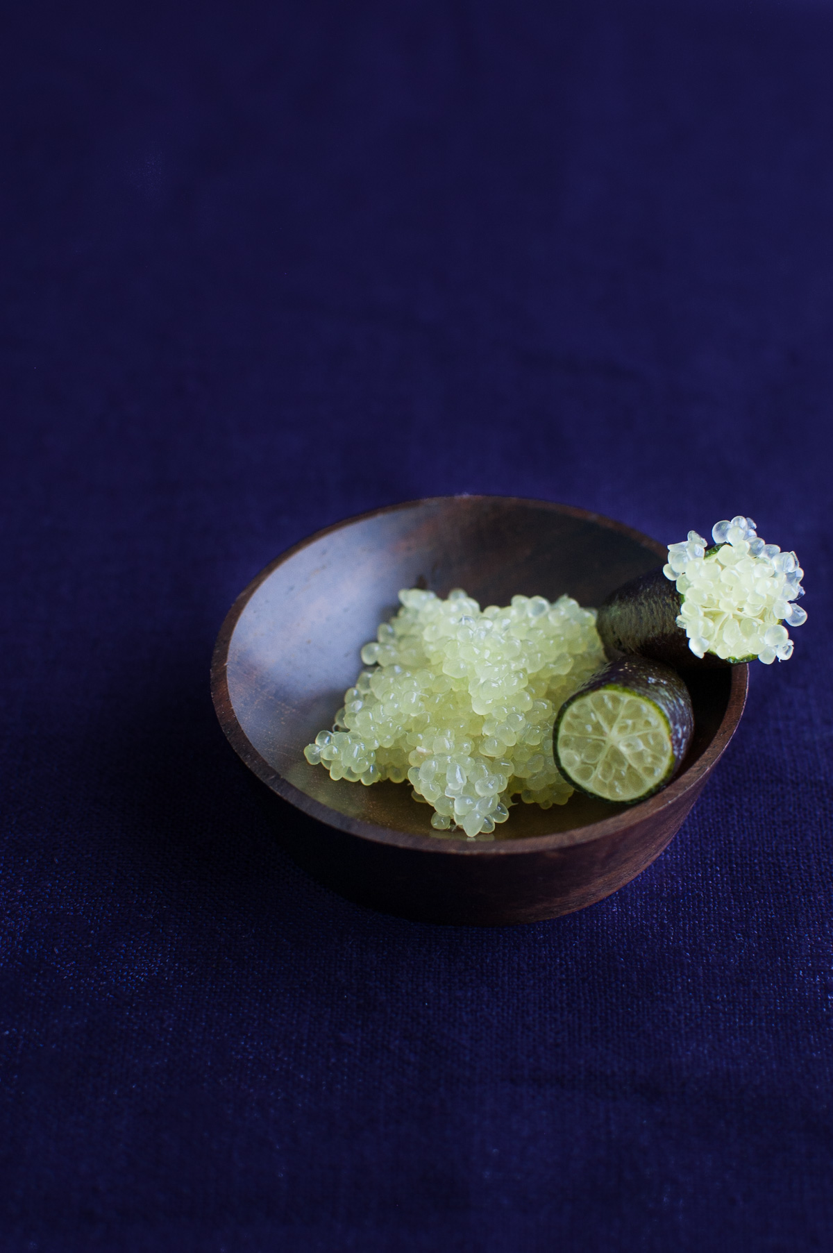A cut finger lime on a small wooden dish.