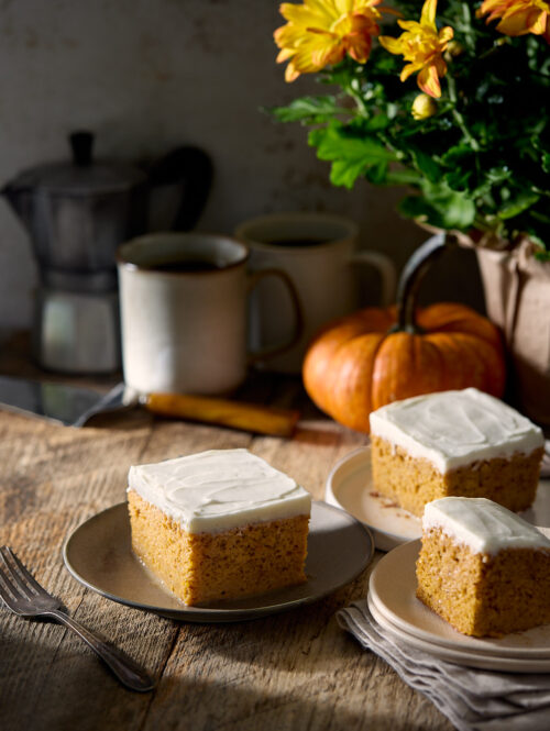 Three plates of pumpkin tres leches cake next to a small pumpkin.