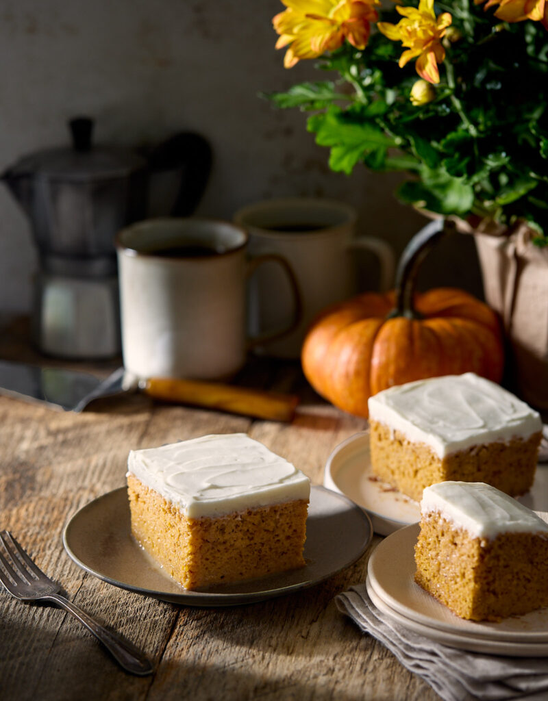 Three plates of pumpkin tres leches cake next to a small pumpkin.