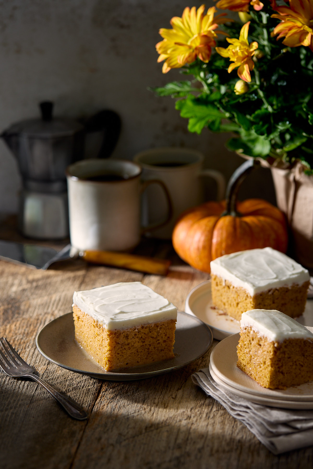 Three plates of pumpkin tres leches cake next to a small pumpkin.