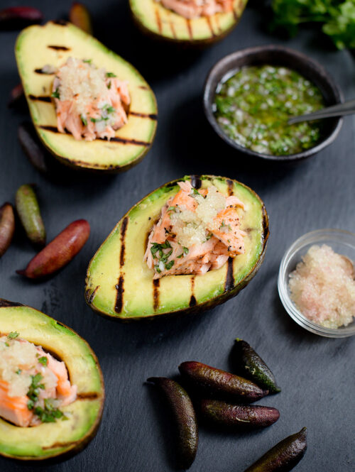 Avocado halves topped with roasted salmon and finger lime pearls.