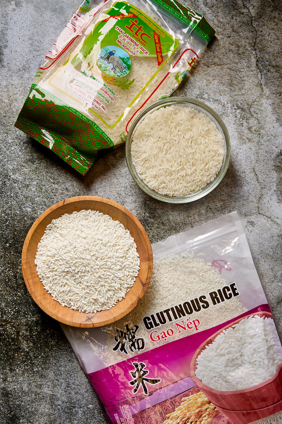 A bowl of glutinous rice next to a bowl of Jasmine rice.
