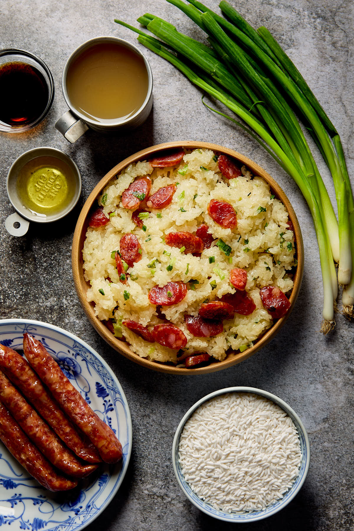 A plate of cooked sticky rice with Chinese sausage next to some ingredients.